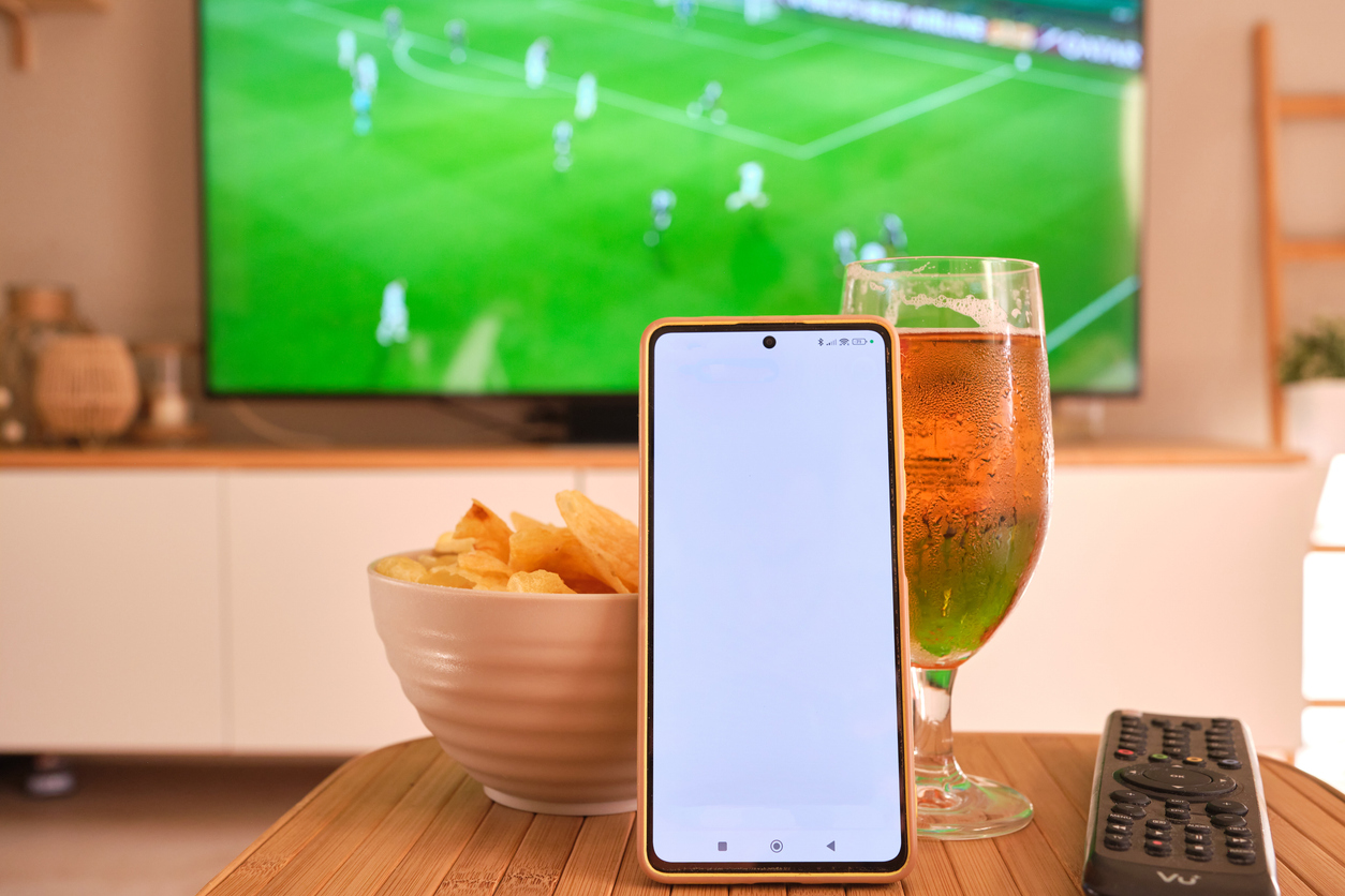 Smartphone and football match on TV while following live scores